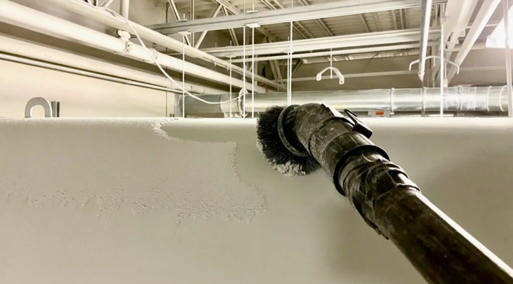 Poussière accumulée sur une surface en hauteur aspirée avec une brosse